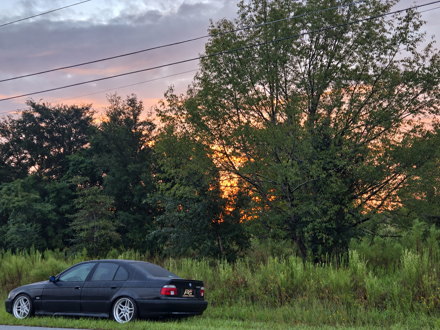 Polaks_Garage black sedan parked beside trees at sunset